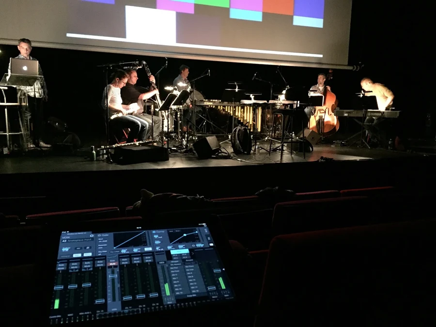 Ciné-concert : musiciens jouant sous un écran de cinéma, console de mixage au premier plan